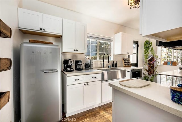 kitchen with wood-type flooring, sink, white cabinetry, and refrigerator