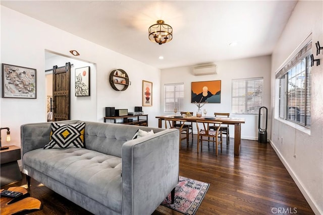 living room featuring dark wood-type flooring, a barn door, and a wall mounted air conditioner