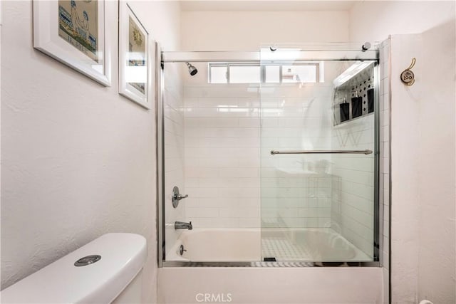 bathroom with combined bath / shower with glass door and toilet