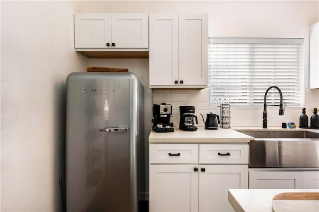 kitchen featuring backsplash, stainless steel fridge, sink, and white cabinetry