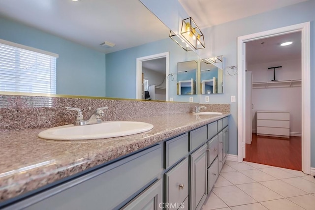 full bathroom featuring a walk in closet, tile patterned flooring, a sink, and double vanity