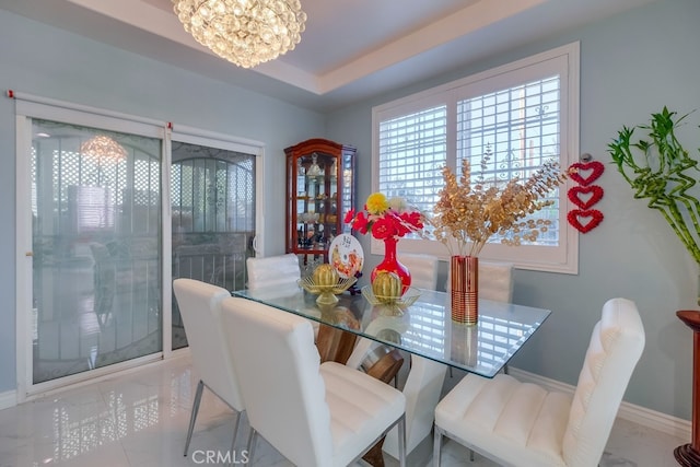 dining room with baseboards, a tray ceiling, and an inviting chandelier