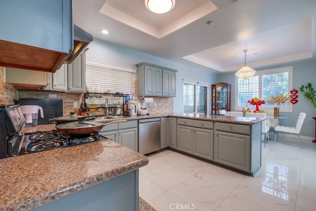 kitchen with a peninsula, a sink, marble finish floor, dishwasher, and a tray ceiling