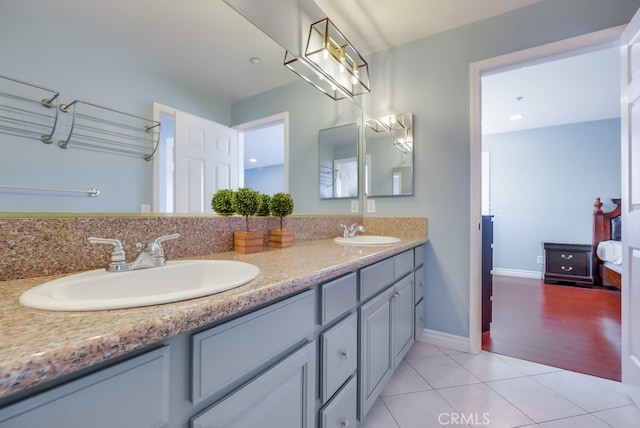 bathroom with tile patterned flooring, a sink, baseboards, and double vanity