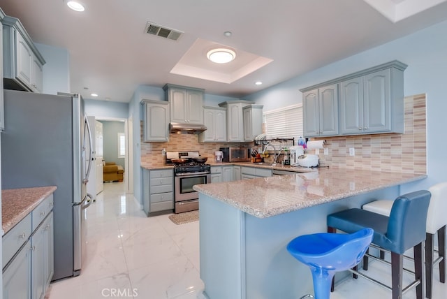 kitchen featuring marble finish floor, light countertops, decorative backsplash, appliances with stainless steel finishes, and a peninsula