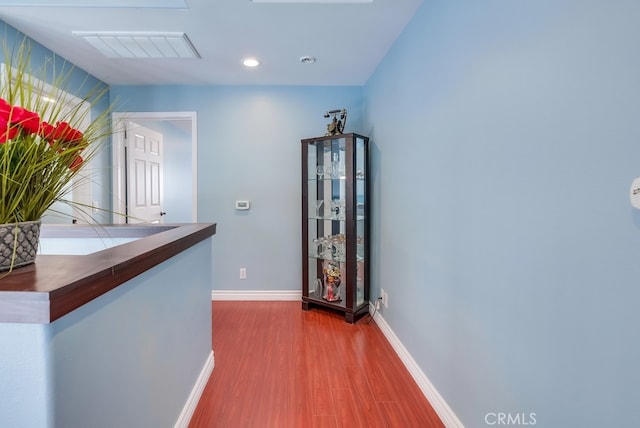 hall with baseboards, visible vents, wood finished floors, and recessed lighting