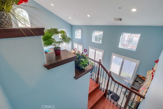 stairway featuring recessed lighting, visible vents, plenty of natural light, and wood finished floors