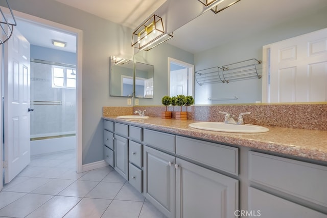 full bath with double vanity, tile patterned flooring, combined bath / shower with glass door, and a sink