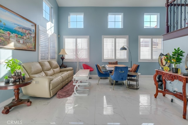 living area featuring a wealth of natural light, marble finish floor, and a towering ceiling