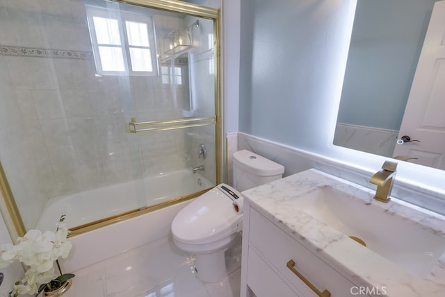 bathroom featuring toilet, shower / bath combination with glass door, and vanity