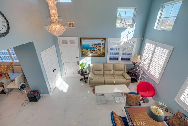 living room featuring a notable chandelier, a high ceiling, visible vents, baseboards, and marble finish floor