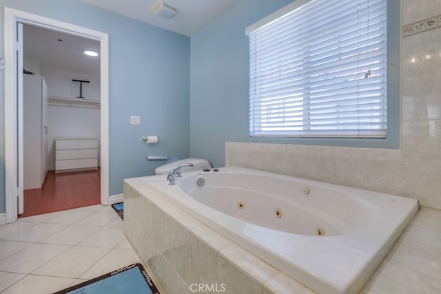 full bath featuring visible vents, a spacious closet, a whirlpool tub, and tile patterned floors