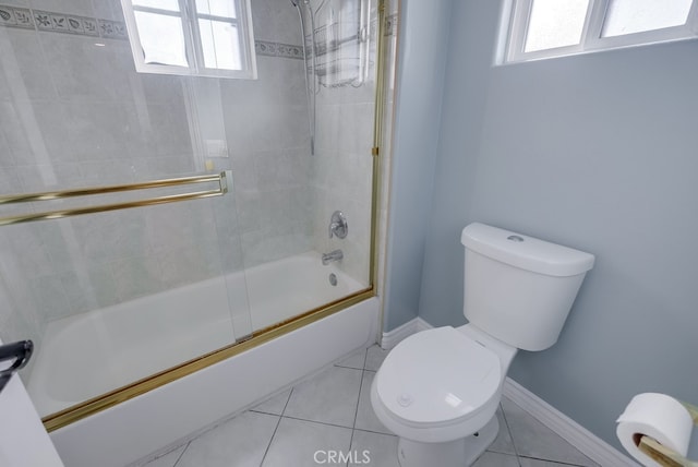 full bathroom featuring tile patterned flooring, baseboards, toilet, and bath / shower combo with glass door