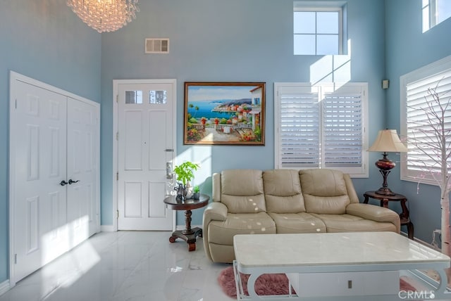 living area with marble finish floor, a high ceiling, visible vents, and baseboards