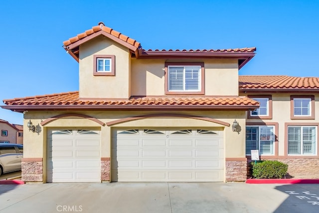 mediterranean / spanish home with stone siding, driveway, and stucco siding