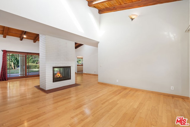 unfurnished living room with a brick fireplace, wooden ceiling, beam ceiling, and light hardwood / wood-style floors