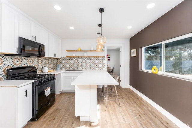 kitchen with pendant lighting, white cabinetry, backsplash, a kitchen bar, and black appliances