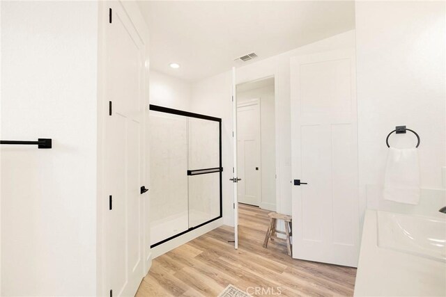 bathroom with an enclosed shower, sink, and hardwood / wood-style floors