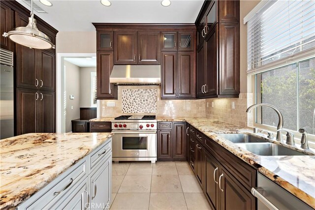 kitchen featuring hanging light fixtures, backsplash, sink, and luxury range