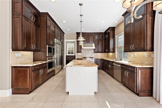 kitchen with appliances with stainless steel finishes, a center island, pendant lighting, dark brown cabinetry, and sink