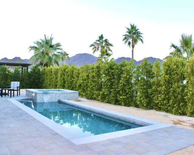 view of pool featuring a patio area, a mountain view, and an in ground hot tub