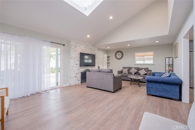 living room with a fireplace, light hardwood / wood-style floors, and high vaulted ceiling