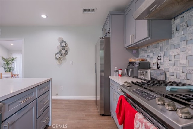 kitchen featuring premium range hood, stainless steel appliances, gray cabinetry, tasteful backsplash, and light wood-type flooring