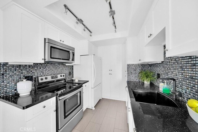 kitchen with white cabinetry, stainless steel appliances, decorative backsplash, sink, and light tile patterned floors