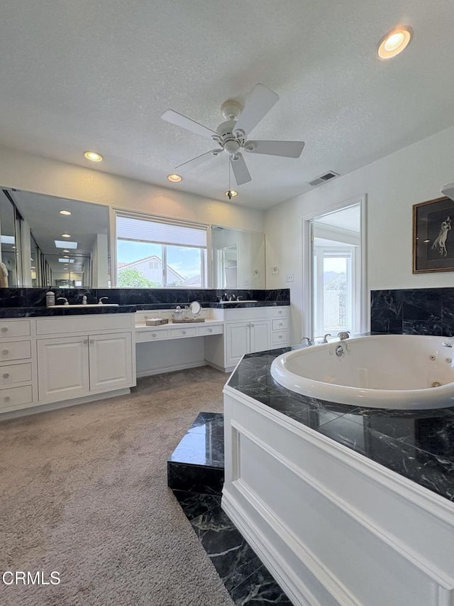 bathroom featuring ceiling fan, a textured ceiling, vanity, and a bathing tub