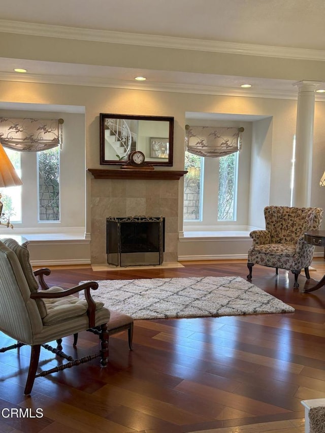 living room with a wealth of natural light, crown molding, and a tiled fireplace