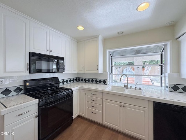 kitchen featuring sink, white cabinets, black appliances, and tile countertops