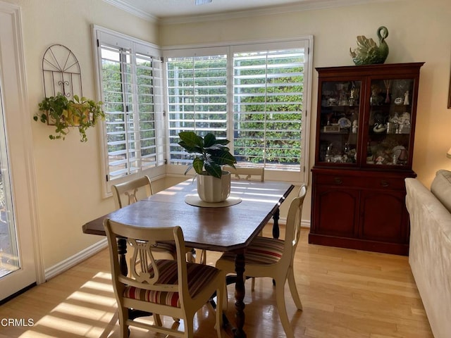 dining room with a wealth of natural light, crown molding, and light hardwood / wood-style flooring