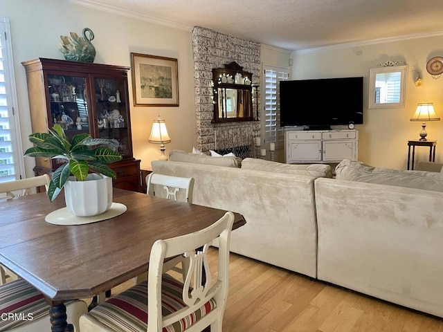 living room with light wood-type flooring, a fireplace, crown molding, and a textured ceiling