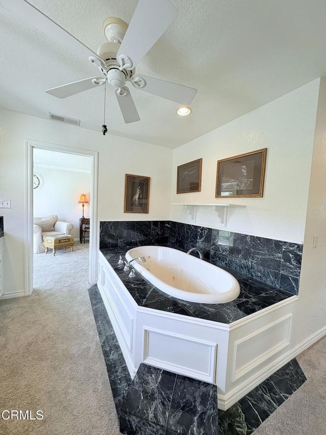 bathroom with a textured ceiling, a bathing tub, and ceiling fan