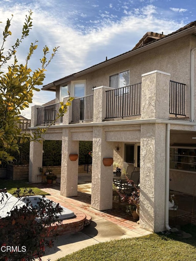 rear view of house featuring a balcony and a patio