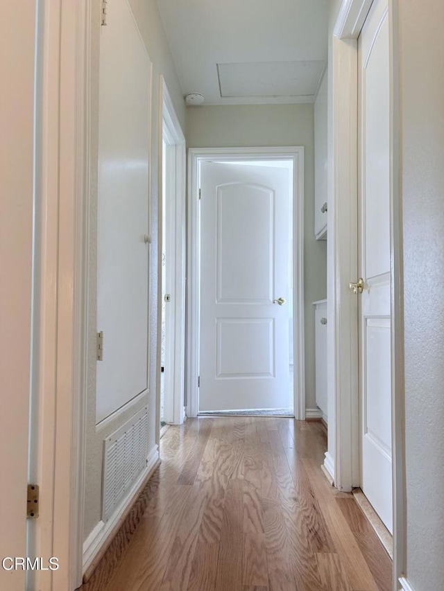 hallway featuring attic access, visible vents, and light wood finished floors