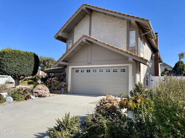 view of home's exterior with stucco siding, a garage, concrete driveway, and a tiled roof