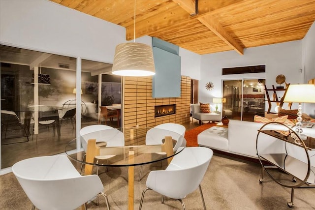 dining space with a tiled fireplace, wooden ceiling, and beamed ceiling