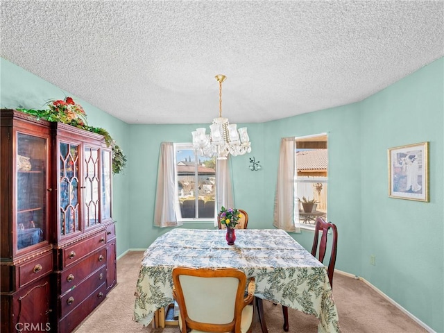 dining room featuring an inviting chandelier, light colored carpet, and a textured ceiling