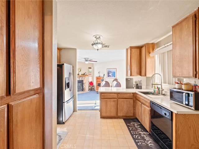 kitchen featuring appliances with stainless steel finishes, a stone fireplace, sink, kitchen peninsula, and plenty of natural light