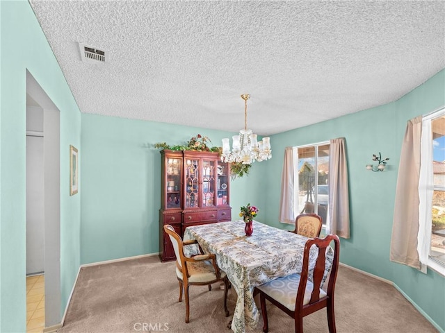 dining room featuring light carpet, a textured ceiling, and a chandelier