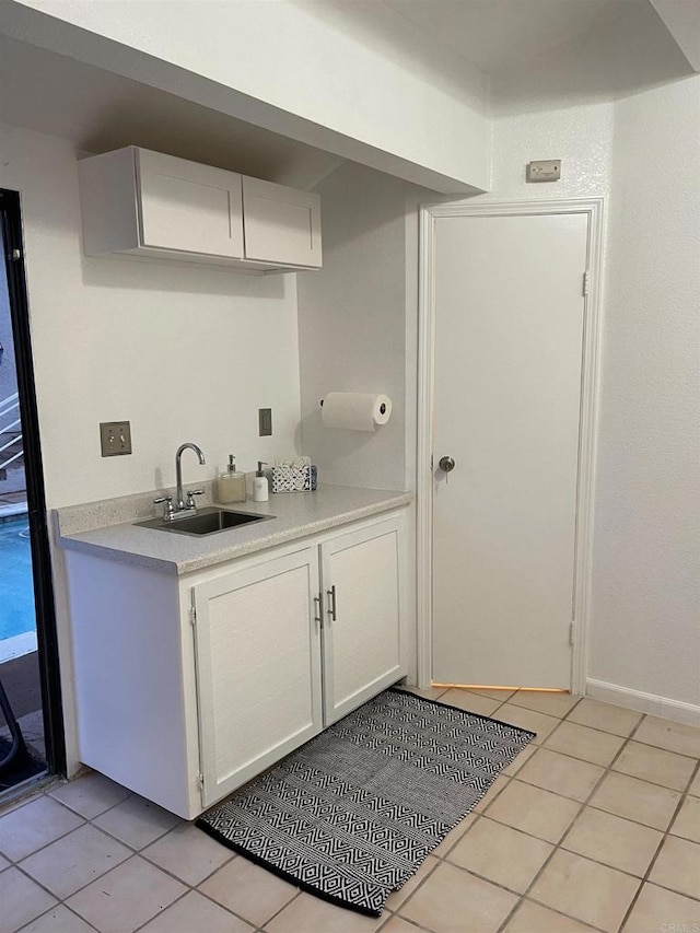 kitchen featuring white cabinetry, sink, and light tile patterned flooring