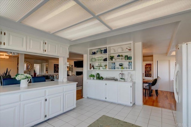 kitchen with white cabinetry, white refrigerator, light tile patterned flooring, and built in features