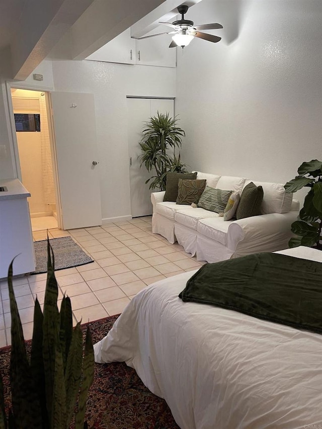 bedroom with light tile patterned flooring, ensuite bathroom, and ceiling fan