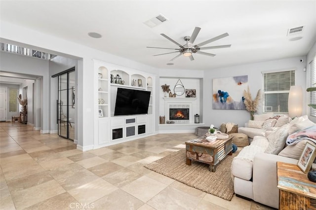 living room featuring ceiling fan and built in shelves