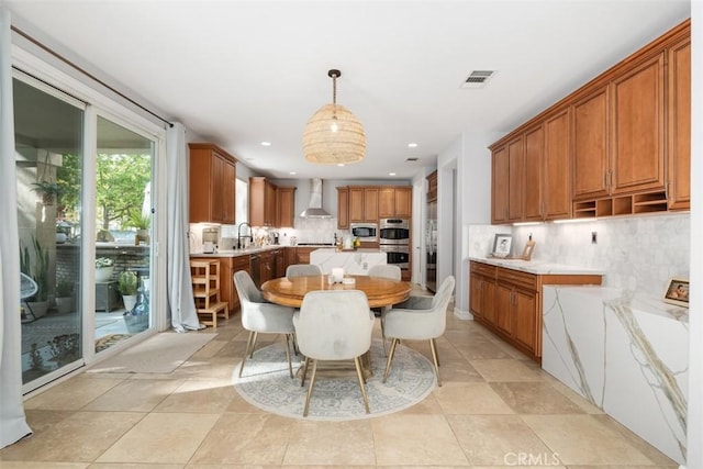 kitchen featuring decorative light fixtures, backsplash, wall chimney exhaust hood, and stainless steel appliances