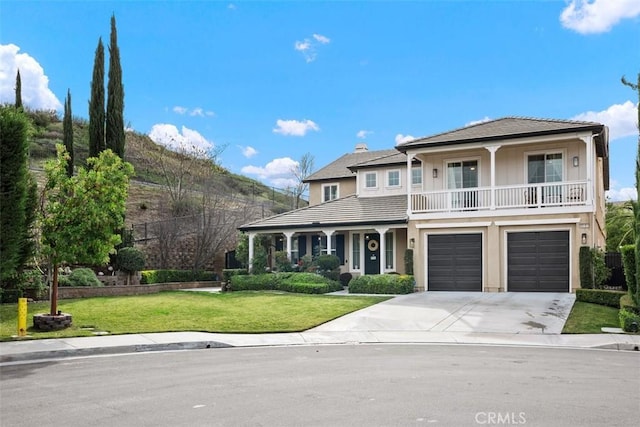 view of front of home with a garage, a balcony, and a front yard