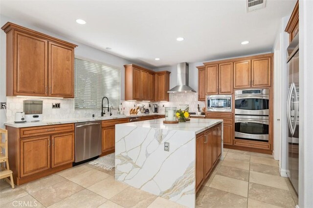 kitchen with decorative backsplash, wall chimney range hood, stainless steel appliances, and a kitchen island