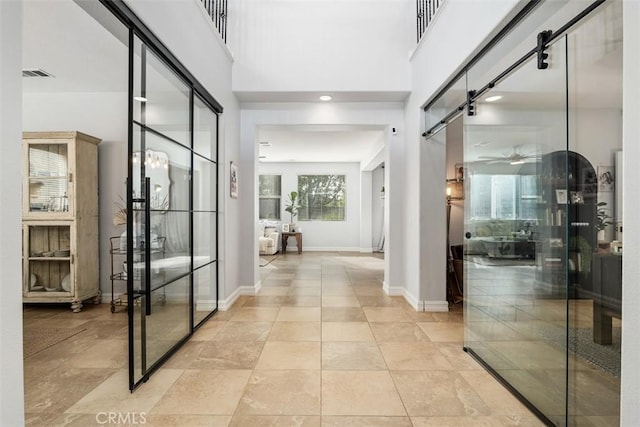 hallway featuring a barn door and a towering ceiling