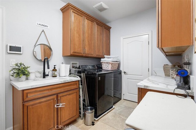 clothes washing area with washer and dryer, cabinets, light tile patterned floors, and sink